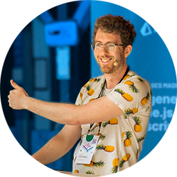 Josh smiling and giving a thumbs up at a podium wearing a white shirt with a pineapple pattern